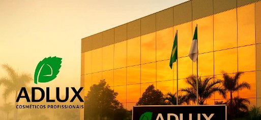 Sede da ADLUX ao pôr do sol, com fachada de vidro dourado, totem da marca e palmeiras — luz golden hour.