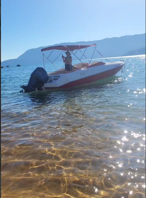 Lancha ancorada em praia de águas calmas durante passeio privativo em Ilhabela